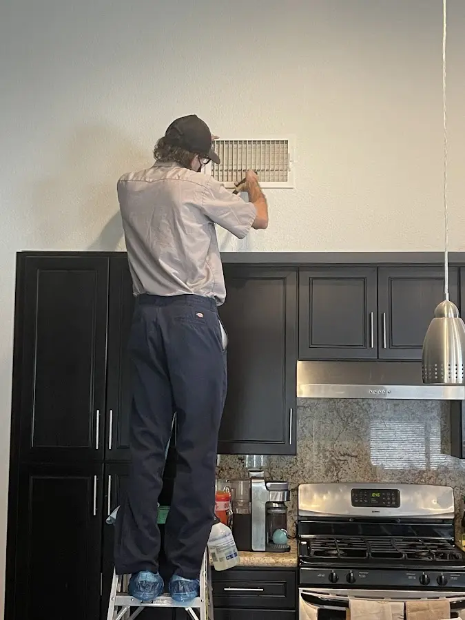 Technician inspecting an air vent during HVAC service in East Nottingham